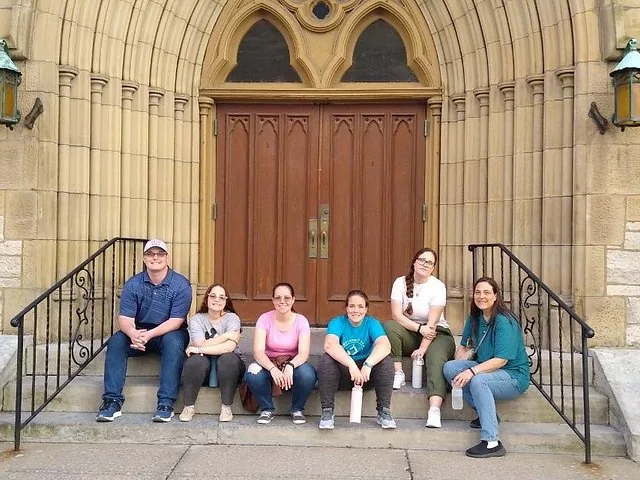 A group of six people sitting on steps in front of a church door