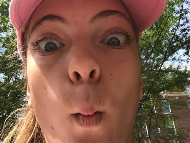 Close-up selfie of a woman making a silly face outdoors.